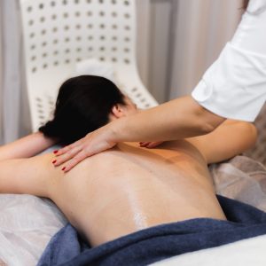 The girl in the spa salon receives a back and neck massage, lies in the cosmetology table, relaxed and enjoys the process
